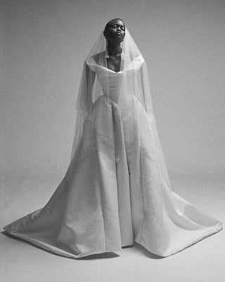 Model posing in the Nova Bagatelle gown, showcasing the cinched waist and full pleated skirt against a neutral background.