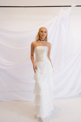 Sophisticated strapless column wedding gown with cascading tiered ruffles and a sleek fitted bodice for an elegant bridal look.