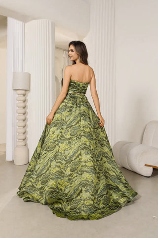 Woman in a green strapless gown standing in a modern interior setting