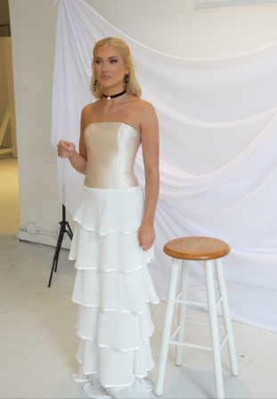 Modern satin wedding gown featuring a strapless neckline, tailored fit, and cascading ruffles for a dramatic yet refined style.