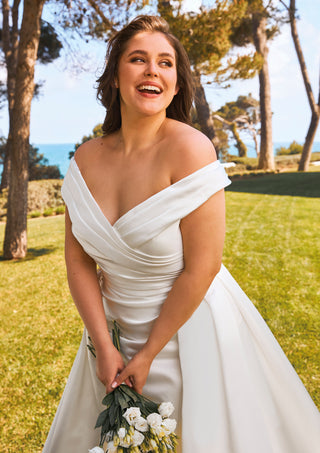 Elegant bridal gown with dropped shoulders and voluminous skirt.