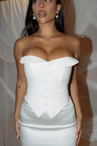 Minimalist bridal gown with a strapless corset top, tailored button accents, and a graceful column silhouette