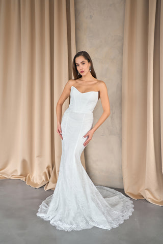Lace wedding dress featuring a dramatic mermaid silhouette and delicate sleeveless detailing for a timeless bridal look.