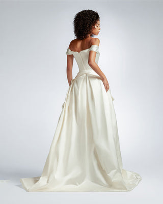 Model standing with the Diva Train by Vivienne Westwood, showcasing the elegant pleated structure and couture-inspired apron design from the back, enhancing a slim wedding dress.