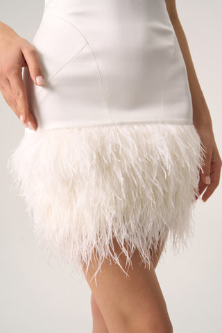 Modern mini sheath dress with spaghetti straps, a square neckline, and luxurious feather details at the hemline.