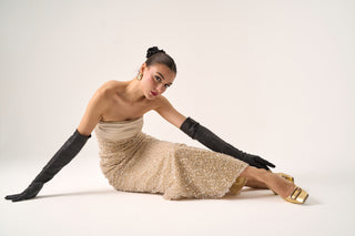 Model wearing the Cristos strapless beaded gown by Nadia’s with black gloves, showcasing the intricate beading.