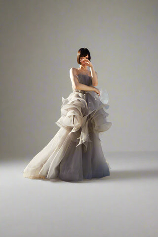 Strapless ball gown with voluminous cascading layers and a flowing, floor-length silhouette, exuding romantic sophistication.