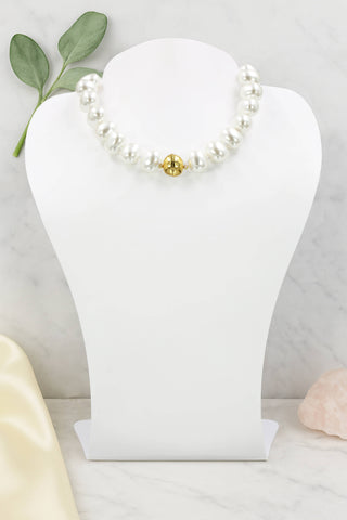 Pearl bracelet with a gold accent on a white jewelry stand with a light gray background