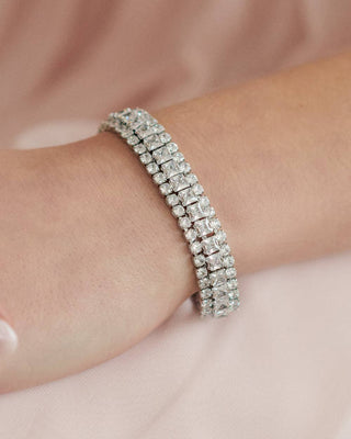 Silver bracelet with clear stones on a wrist against a soft pink background