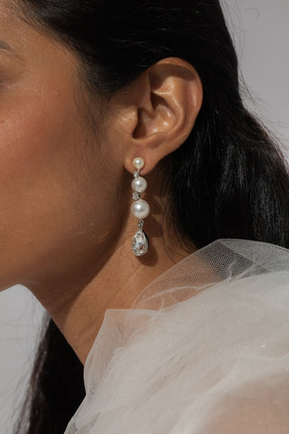 Close-up of a person wearing a pearl earring with a blurred background