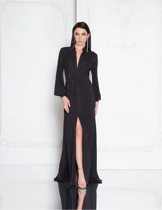 Woman wearing a black evening gown with a deep neckline and high slit on a white background