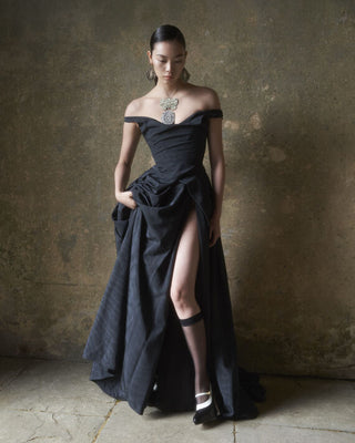 Full body view of the Tabitha gown in black, with the model lifting the skirt to reveal the sultry side slit.