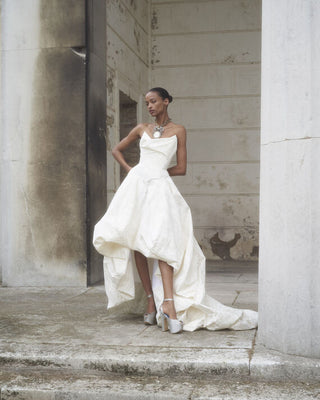 Front full view of the Victoria gown by Vivienne Westwood, showcasing its delicately draped corset and voluminous asymmetrical tiered skirt in an elegant bridal look.