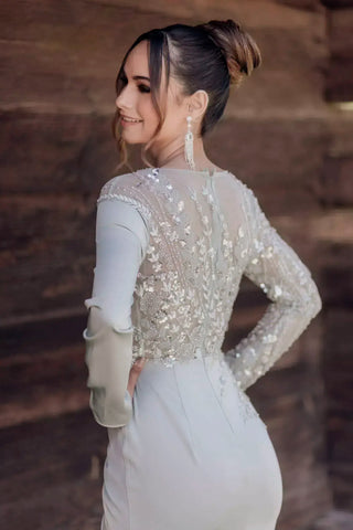 Woman wearing a sparkling top with long sleeves against a blurred natural background