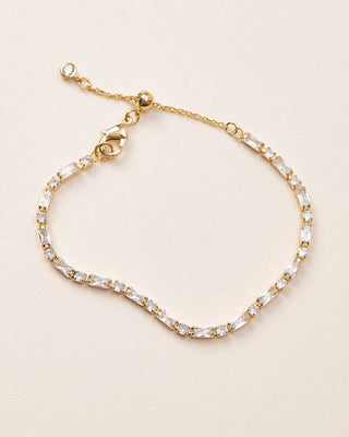 Gold bracelet with clear gemstones on a beige background