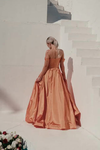 Woman in an evening gown standing on a staircase with flowers at her feet.