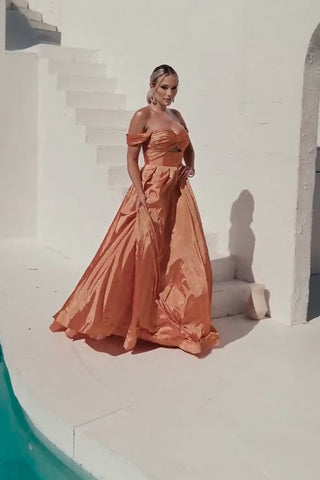 Woman in a long, off-shoulder dress standing on a white staircase.