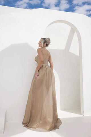 Woman in an evening gown standing in front of a white archway with blue sky.