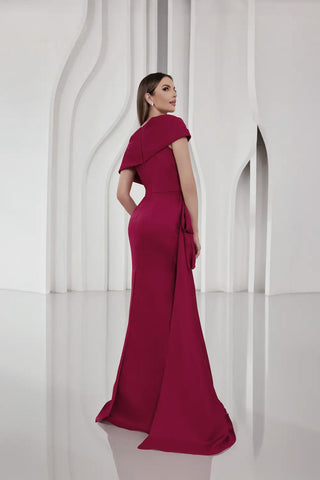 Woman in a magenta evening gown standing against a white architectural background