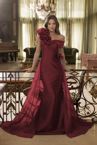 Woman in a burgundy evening gown with floral details in an elegant room.