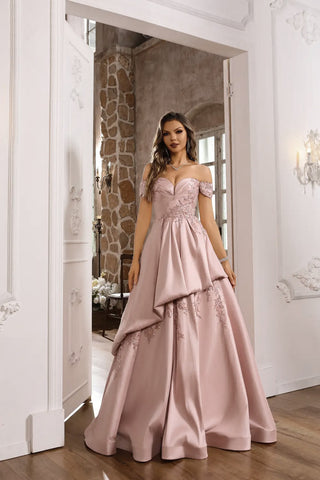Woman in a pink evening gown standing in a decorated room.