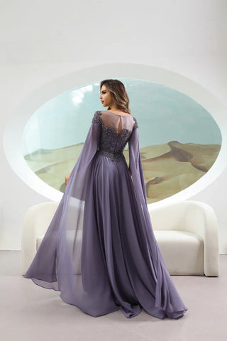 Woman in a long, elegant purple dress standing in front of a circular mirror with a desert scene reflection.