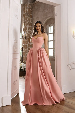 Woman in a pink evening gown standing in a doorway.