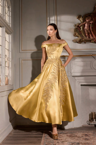 Woman in a gold evening gown standing in an elegant room with classical decor.