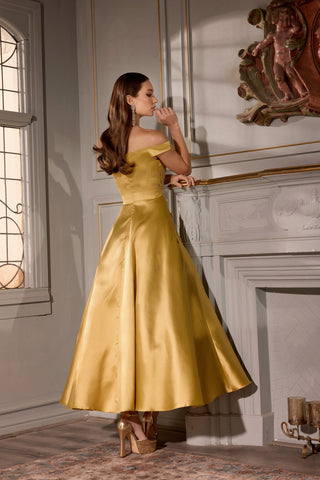 Woman in a yellow dress standing in a room with a fireplace and stained glass window.