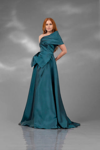 Woman wearing a teal one-shoulder gown against a gray background