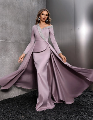 Woman in a long, flowing purple gown against a gray background