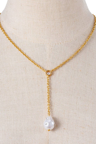 Gold necklace with a pearl pendant on a mannequin bust.