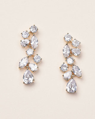 Pair of teardrop-shaped crystal earrings on a beige background
