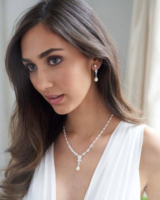 Woman wearing a necklace and earrings with a neutral background