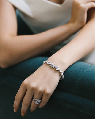 Close-up of a hand wearing a bracelet and ring on a dark background