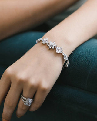 Close-up of a hand wearing a diamond bracelet and ring on a dark surface