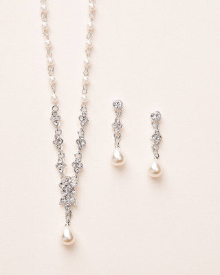 Pearl necklace and earrings on a light pink background