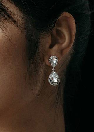 Close-up of a person wearing a sparkling earring with a dark background
