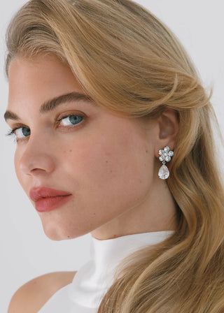 Close-up of a woman wearing elegant earrings with a plain background