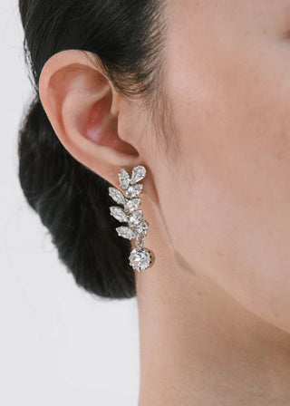 Close-up of a person wearing a sparkling silver earring on a plain background