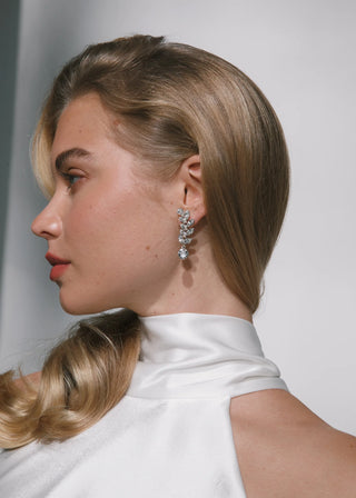 Woman with styled hair and earrings against a plain background
