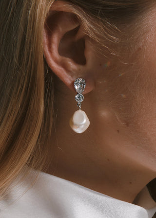 Close-up of a person wearing a pearl earring with a visible clasp.