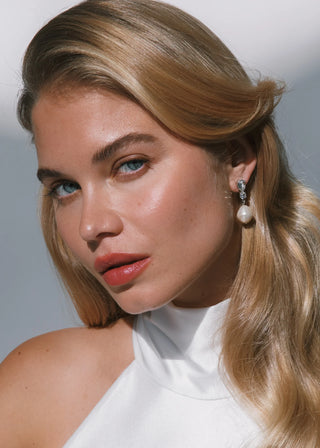 Woman with blonde hair and a white top against a neutral background
