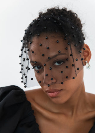 Model wearing the Chiara Veil, elegantly framing her face with shimmering pearls.