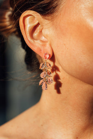 Close-up of a person wearing pink floral earrings with a blurred background