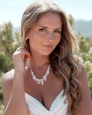 Woman wearing a white dress with a necklace in a natural setting