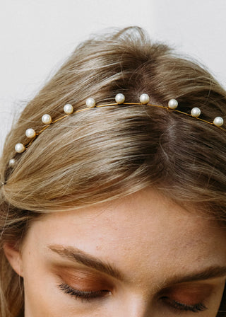 A close-up of a model wearing the Iris Skinny Headband with loose curls, highlighting the headband’s enchanting pearl accents in her hair.