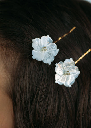 Delicate mother-of-pearl flowers with pearl accents, secured on durable steel bobby pins, perfect for elegant hairstyles.