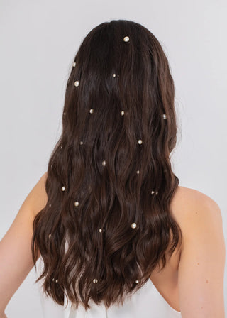 Long dark hair with pearl hair accessories on a plain background