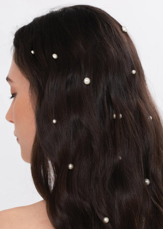 Woman with pearl hairpins in her dark hair on a white background